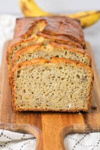 "Freshly baked moist banana bread sliced on a wooden cutting board."